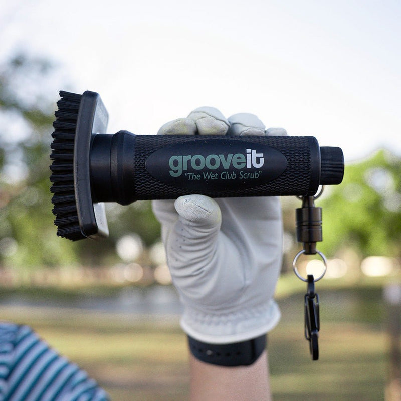 Hand holding a 'grooveit' scrubber with a blurred outdoor background Grooveit Brush – "The Wet Club Scrub" - Grooveit "The Wet Club Scrub" - #golf_club_cleaner# - #golf_club_brush# - #golf_brush# - #grooveit# - #groove_it_brush# - #grooveit_brush# - #groove_cleaner# - #golf_club_cleaning_brush# - #go